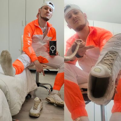Person wearing a white and fluorescent orange tracksuit, white cap, white crew socks and worn white Nike sneakers, posing indoors while showcasing well-used trainers. The sporty outfit emphasizes sneaker culture, athletic fashion and a sneaker fetish aesthetic with casual streetwear styling.