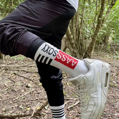 Close-up of white ASOX crew socks worn with white Nike Air Max sneakers and black athletic joggers in a woodland setting. The sporty outdoor look highlights premium socks, classic trainers and sportswear with a clean sneaker fetish aesthetic.
